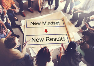 Picture of a group in cercle around a giant paper written : NEW Mindset + New Results 