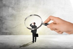 Image of a hand holding a magnifier that focuses on the actions of an employee.
