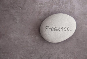 Image of a light gray rock with the word  presence engraved.