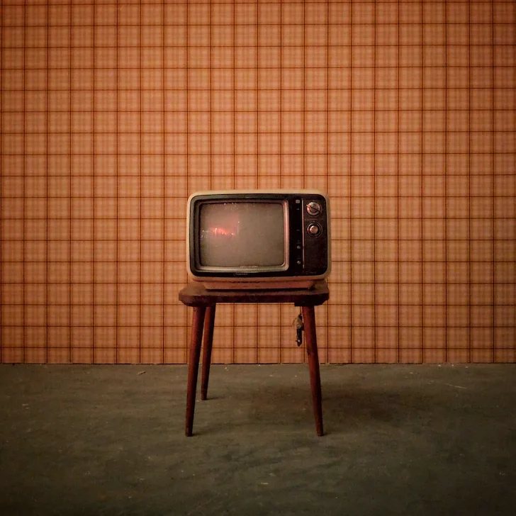 Image d'une télévision rétro posée sur une table devant un mur à motifs écossais.