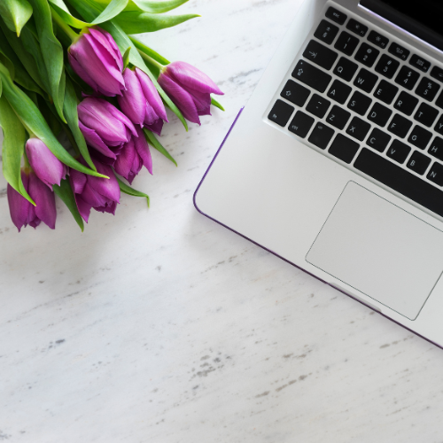 An image of a laptop and tulips on a desk.