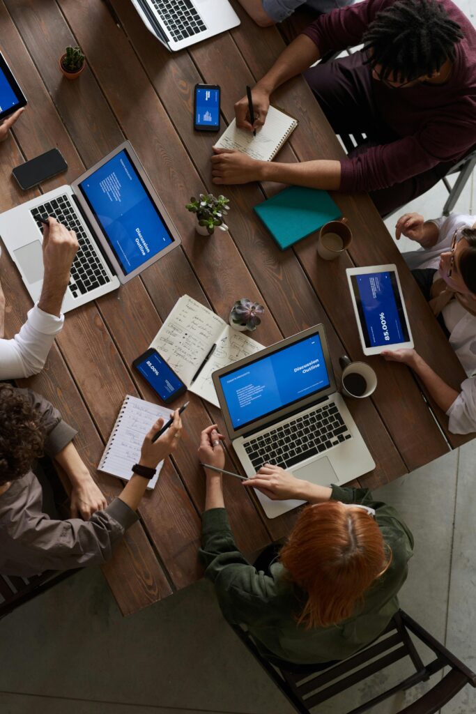 An image of colleagues working on laptops around a table