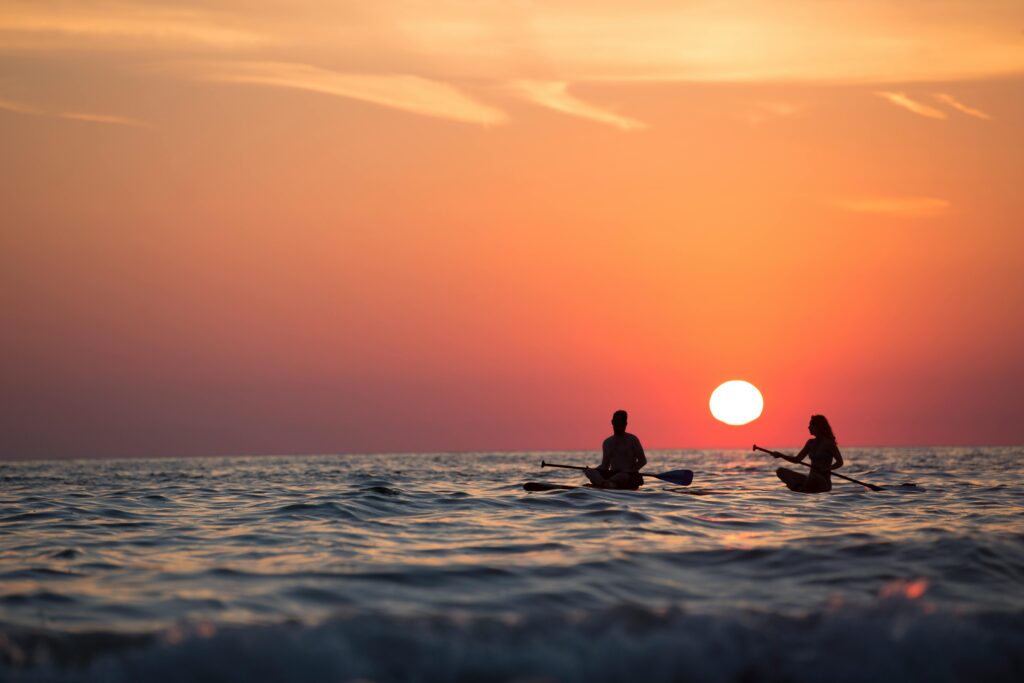 an image of two people kayaking at sunset